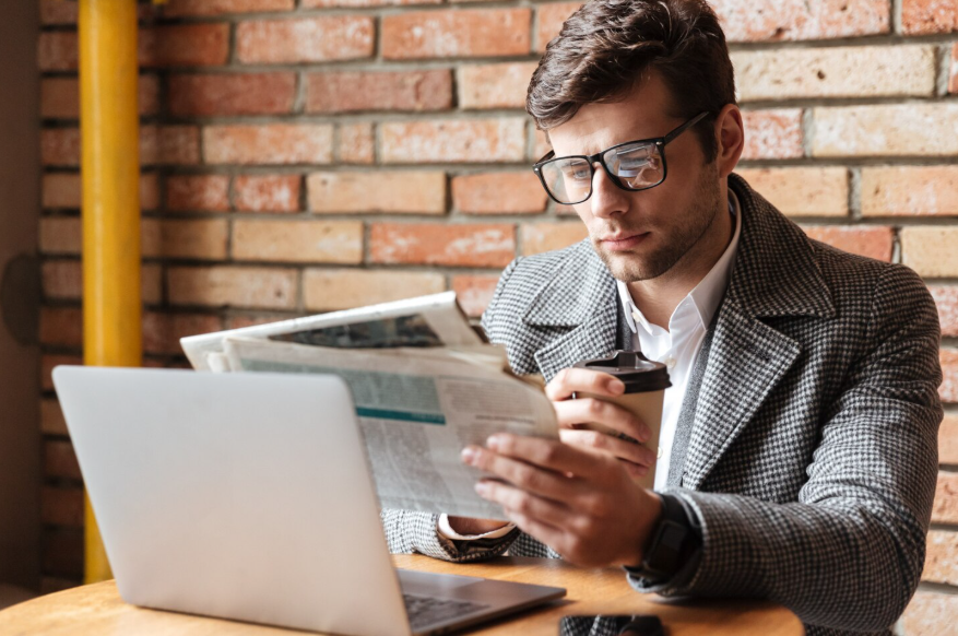 news consumption and mental health connection as man reads news beside laptop