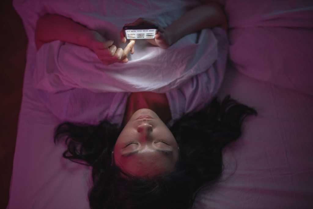 person doomscrolling on a smartphone in bed at night, scrolling negative news
