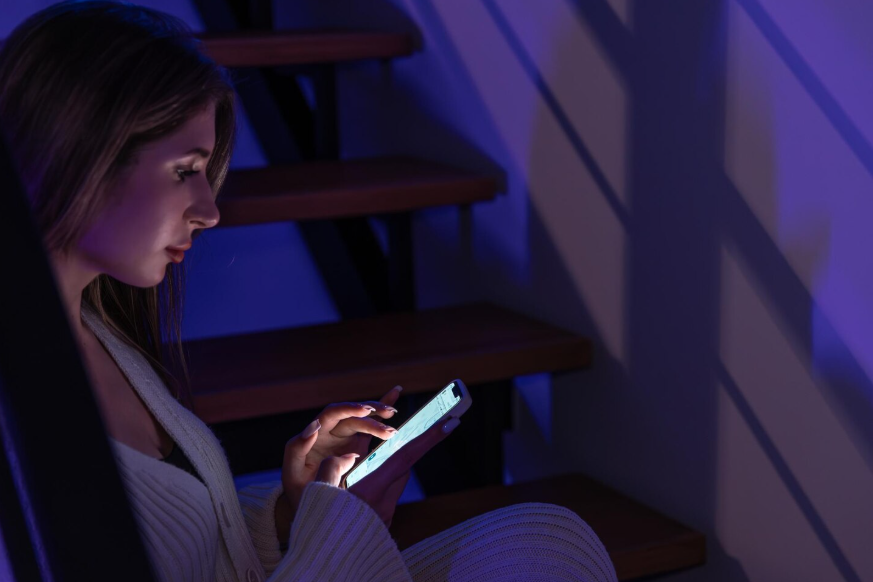 person scrolling bad news on phone in dark room at night