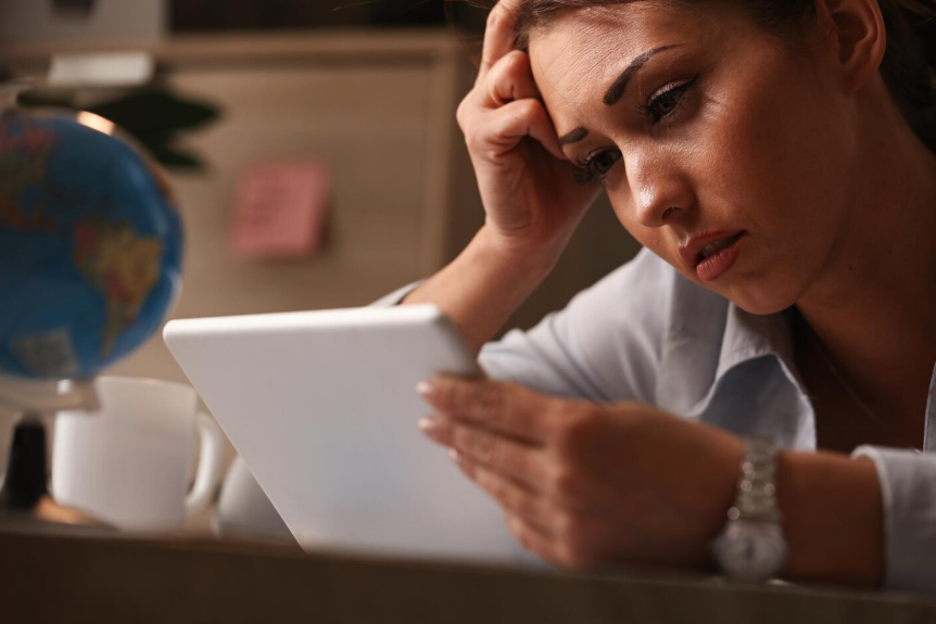Woman suffering news fatigue from constant news reading on tablet